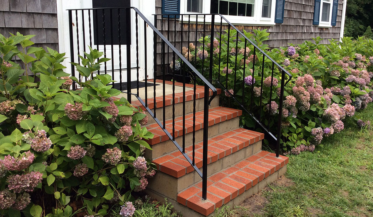 Wrought iron railing painted black steel core drilled into brick steps